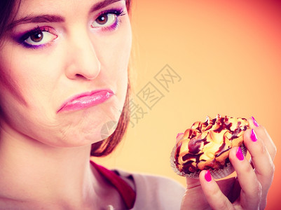 苦的不快乐女人手拿着橙色的蛋糕背景图片