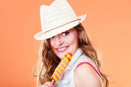 夏天假期快乐的概念笑快乐女人穿着草帽吃冰淇淋橙色背景图片