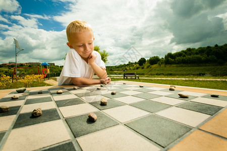小男孩聪明的在公园户外玩跳棋游戏图片