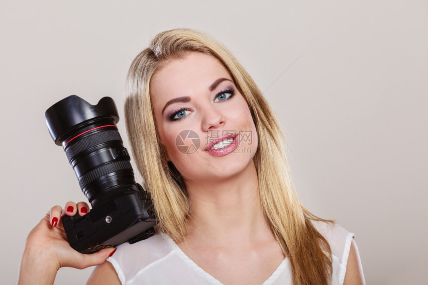 摄影女师拍图像美丽的金发女人带着灰色背景的专业相机图片