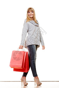 时装女孩牛仔裤高跟鞋白色上孤立的红购物袋图片