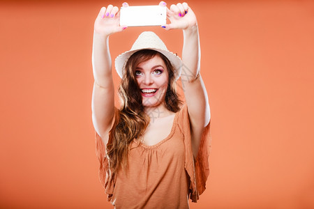 技术互联网和幸福概念年轻暑期女青拍摄自手持智能机相橙色背景背景图片