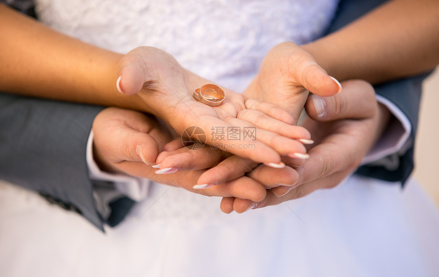 新娘和郎亲手握着金婚戒指的近照图片