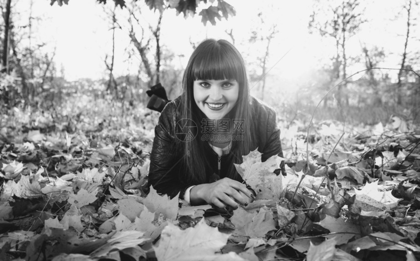 在秋林中躺树叶上的微笑着女人黑白画像图片