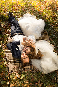 美丽的已婚夫妇躺在公园的黄色树叶上图片