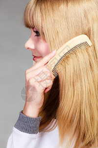 健康美容和理发概念缝合年轻金发女郎用木梳子理长发缝合图片