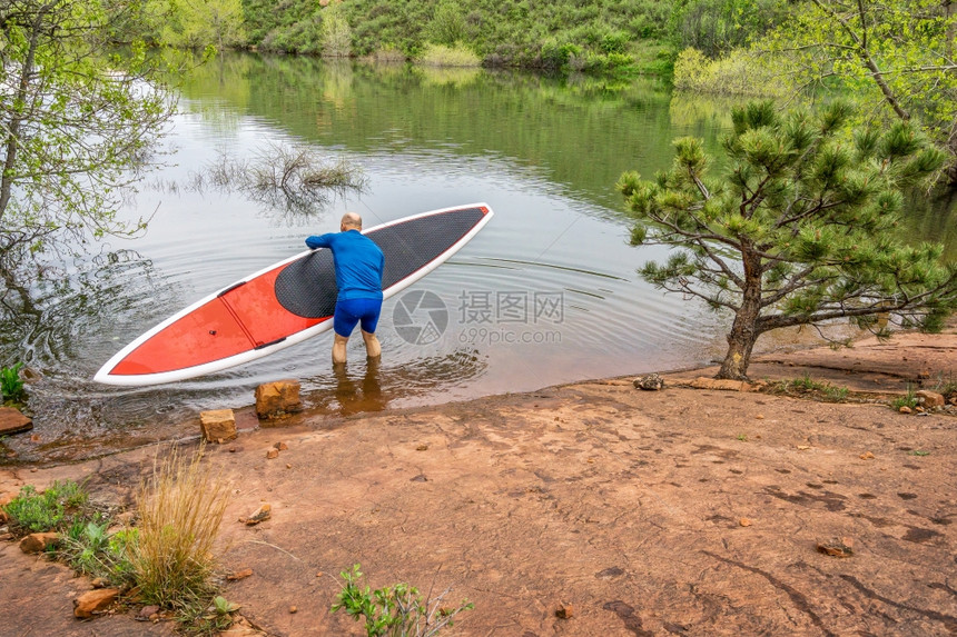 在湖边的岩石岸上发射红色SUPSUP滑板的高级护修牙储藏室科罗拉多州柯林斯堡图片