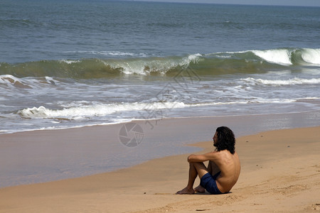 长发的年轻人坐在海岸上看着印度果阿长发的年轻人坐在海岸上看着印度果阿图片