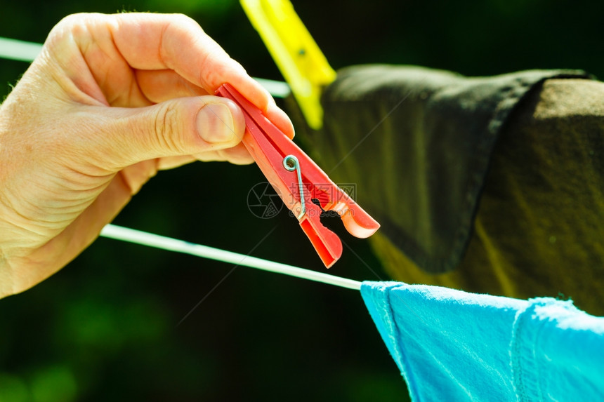 做家务女人手挂干净湿洗的衣服在户外绳索衣服线上烘干图片