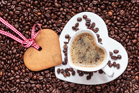 咖啡时间概念以咖啡豆背景上卡布奇诺莫和饼干姜的心形杯顶级视图图片