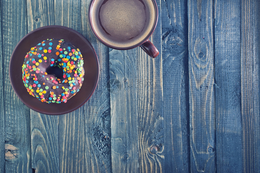 餐桌上的巧克力甜圈和咖啡杯中的图片