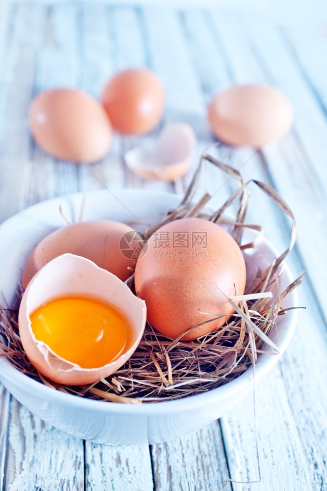 生鸡蛋在碗里和木制桌上图片
