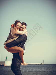 快乐的年轻浪漫情侣相爱的在阳光寒冷的白天在海滩玩乐图片