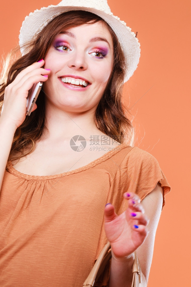 具有吸引力的夏季妇女以移动电话橙色背景交谈图片