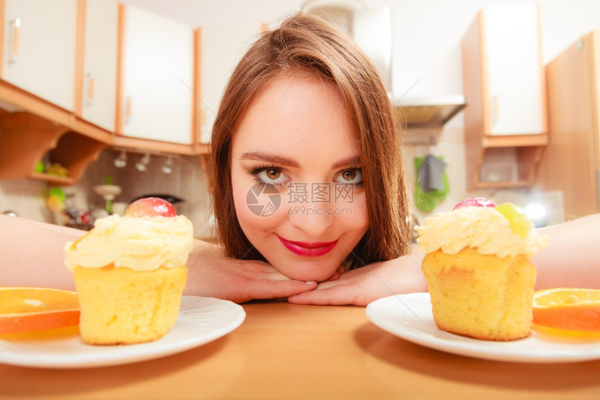 女人看着美味的蛋糕上面有甜的奶油和水果喜欢贪食的概念女人看着美味的甜饼图片