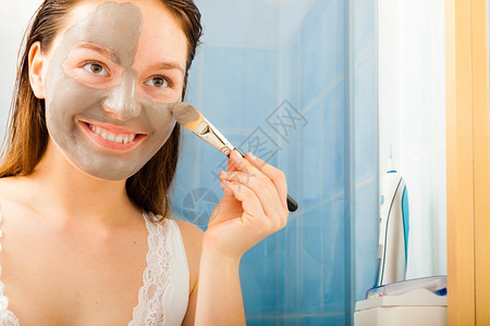 年轻女在浴室用面部灰色泥土遮面罩脸背景图片