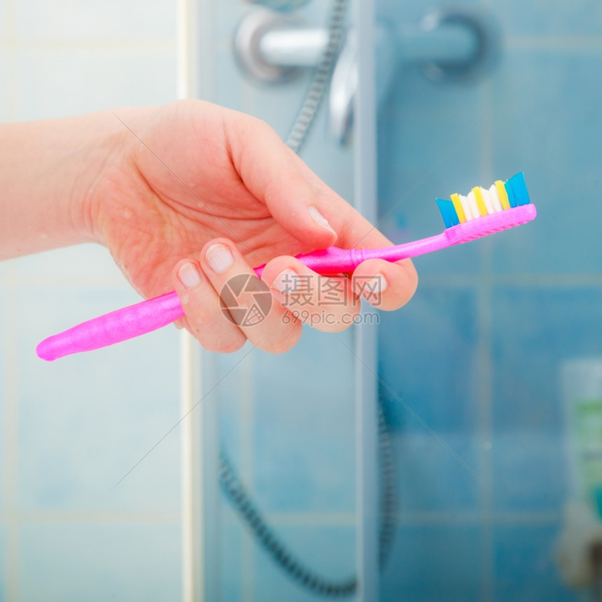 口腔健康概念近身女用手在浴室里拿着粉红色牙刷图片