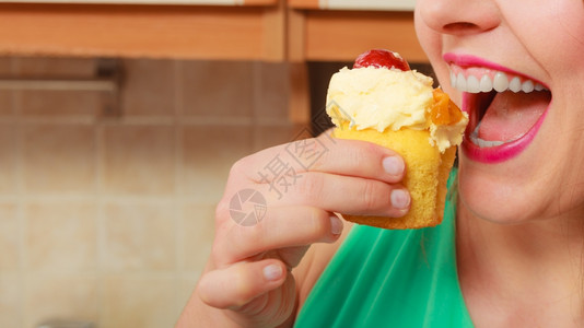 女人吃着美味的蛋糕上面有甜的奶油和水果美味的贪食观念女人吃着美味的甜饼背景图片