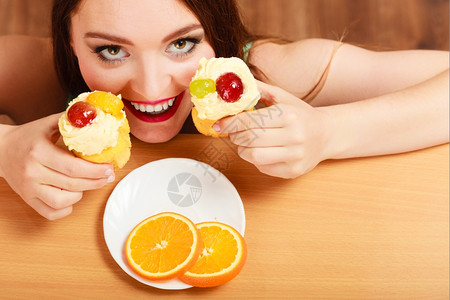 躲在桌后偷摸吃美味蛋糕上面有甜的奶油和水果好女人喜欢和贪食的概念女人吃甜的蛋糕背景图片