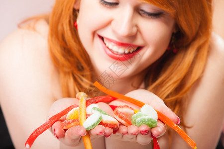 拿着糖果的感年轻女人红发可爱女孩粉红色上加甜果冻的酱图片