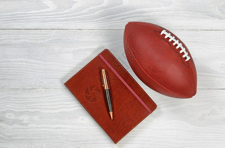 执行笔记本和美式足球在白锈木上的图象图片