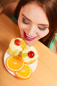 女人躲在桌子后面偷摸地看着美味的蛋糕上面有甜的奶油和水果背景