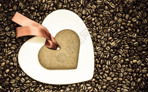咖啡时间概念心形盘子和饼干姜红龙卷风放在咖啡豆背景上图片