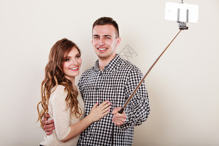 科技互联网和幸福概念年轻夫妇用智能手机相灰色背景自拍图片