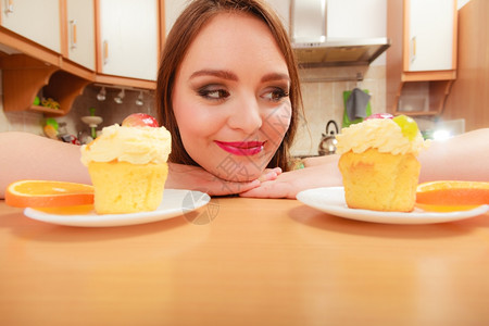 女人看着美味的蛋糕上面有甜的奶油和水果喜欢贪食的概念女人看着美味的甜饼背景图片