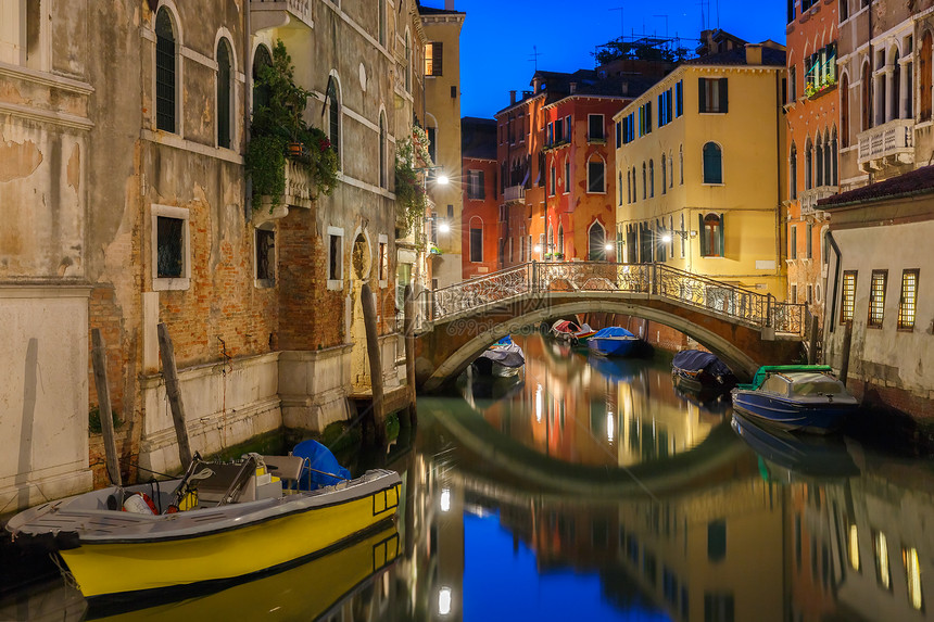 夜间在威尼斯的横向运河和行人桥有街道灯光照亮的桥和房屋有停靠船只意大利图片