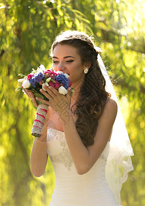 美丽的黑褐发新娘闻着婚礼花束的紧贴肖像图片