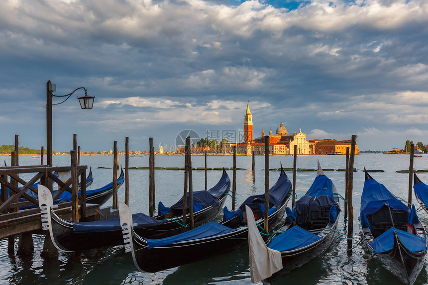 Gondolas由圣马克广场与乔治马吉奥教堂在暴风雨后威尼斯环礁湖背景下挂起图片