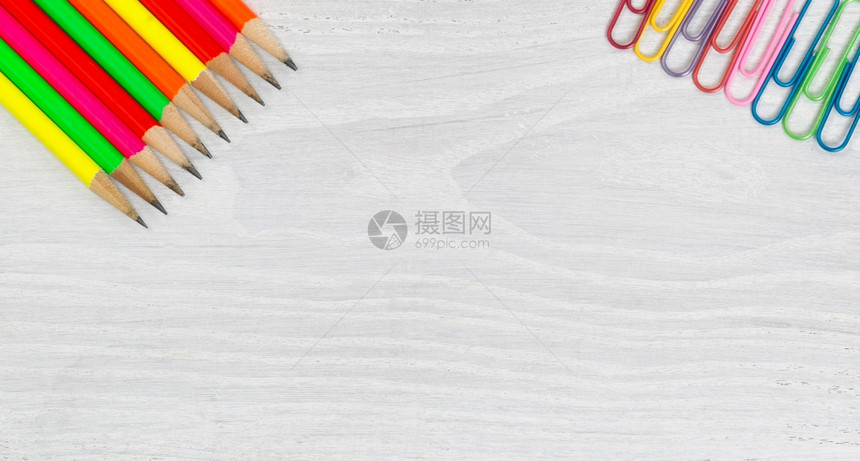 白色木制桌面角上亮的彩色铅笔和纸张剪辑水平格式的高角度视图图片