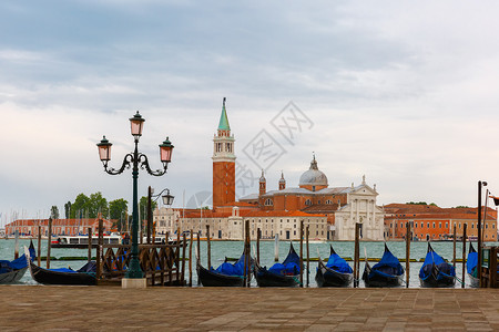 乔治码头Gondolas由圣马克广场和乔治马吉奥雷教堂在意大利威尼斯环礁湖天明时的背面挂起背景