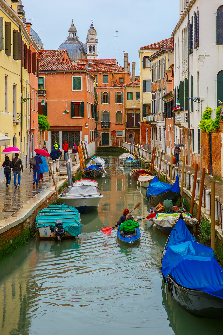 雨天在意大利威尼斯运河上乘雨伞的游客和船划者图片