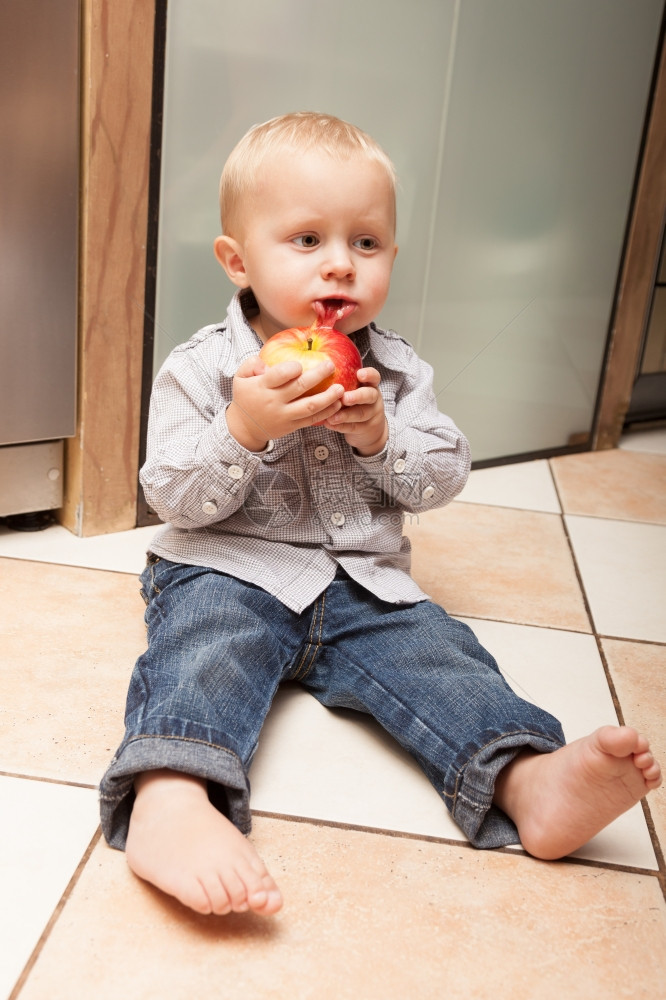快乐的童年可爱小男孩肖像坐在地板上家里吃苹果水健康的营养图片