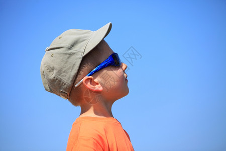 小男孩戴太阳眼镜和帽子望着天空图片