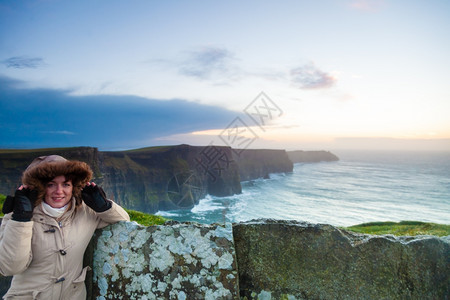 日落时在莫赫尔悬崖上观光的女游客位于CoClare爱尔兰欧洲美丽的景观自然色吸引人背景图片