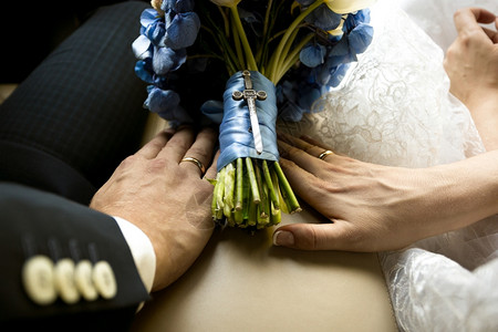 新娘和郎在汽车上握着手婚礼花束的近镜头图片