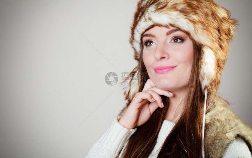 冬时的风情快乐年轻女子穿着时的冬衣毛皮帽工作室拍摄的灰色背景图片