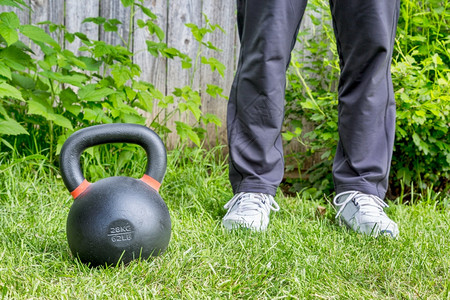 在后院绿草上与重铁竞争的kttbell62lb8公斤一起健身户外培训概念背景图片