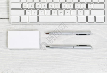 白桌面上部分键盘空白名片堆和银笔的图像横向版式高清图片