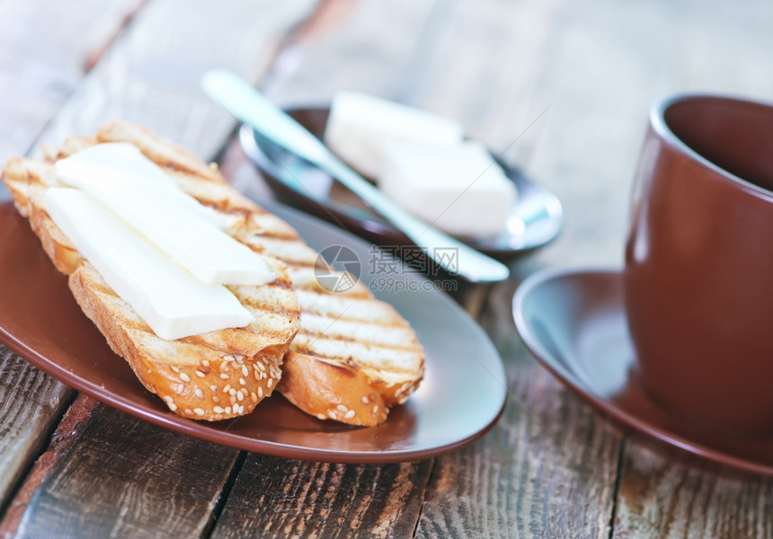 含黄油和茶杯中的新鲜咖啡面包图片