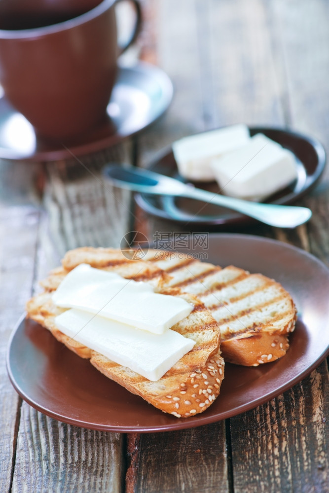 含黄油和茶杯中的新鲜咖啡面包图片