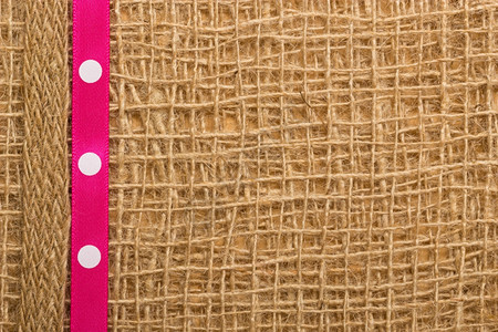 波尔卡在棕色网状材料上用粉红色圆彩丝带涂上棕色网状材料天然薄饼背景图片