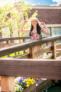 在阳光明媚的白天穿过木桥时戴着帽子的美丽微笑女士图片