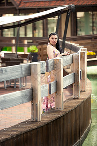 穿着裙子的漂亮女人靠着木栅栏看水渠仰望着图片