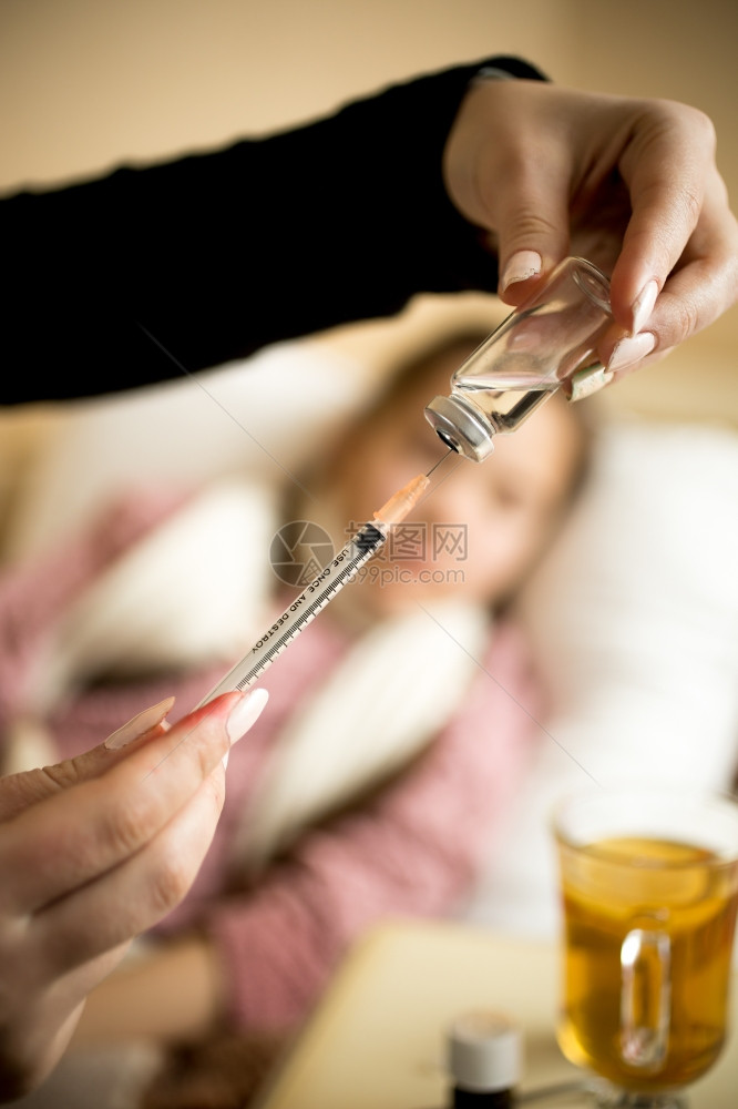 女在生病的童和sbed时从Ampule上填充注射器的近照图片