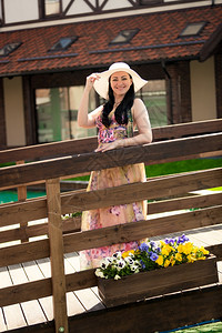 穿着长裙和白帽子的美丽微笑着女士在老木桥上走动图片