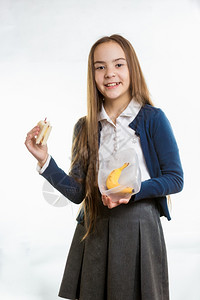 笑的姑娘在白色背景下把三明治从午餐盒里拿出来图片